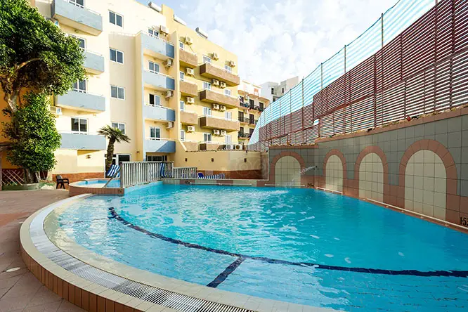 Het buitenzwembad en terras bij het Canifor Hotel in Qawra.